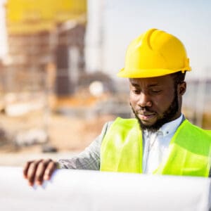 Construction worker reviewing blueprints on site.