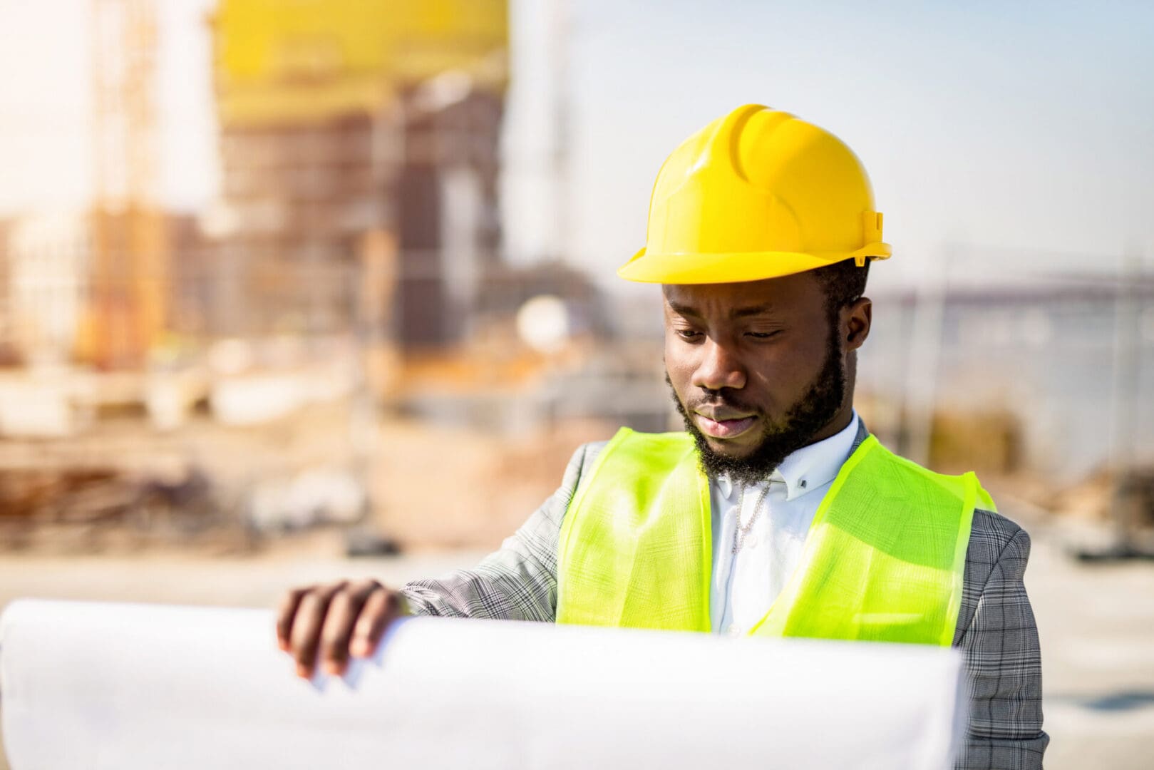 Construction worker reviewing blueprints on site.