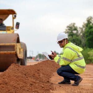 A man kneeling down on the ground near a road.