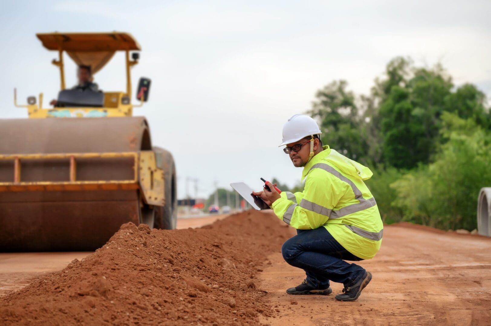 A man kneeling down on the ground near a road.